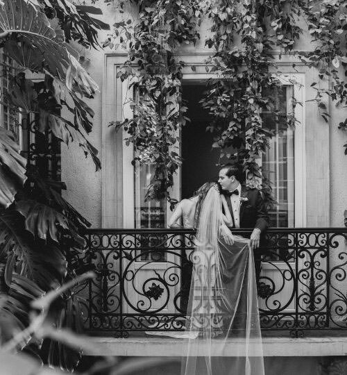 Documentary Wedding Photography of a bride and groom kissing on terrace with ivy-covered walls.