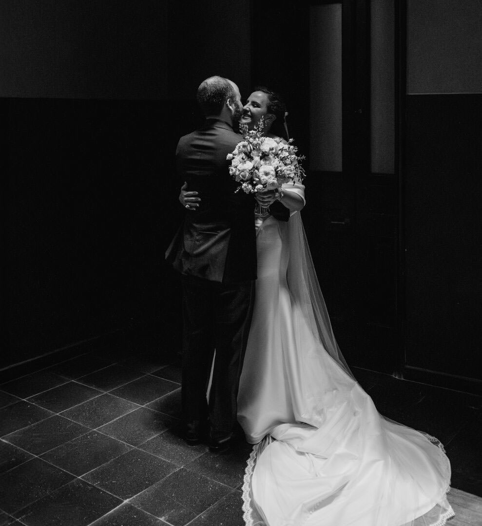 Wedding photographer review of bride and groom embracing under a dramatic spotlight.