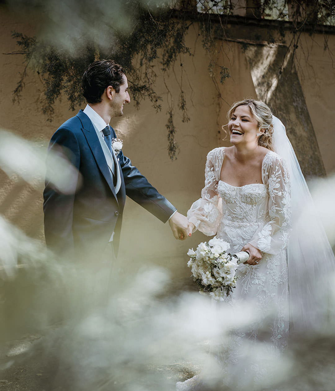 Bride laughing holding groom's hand. Documentary photography.