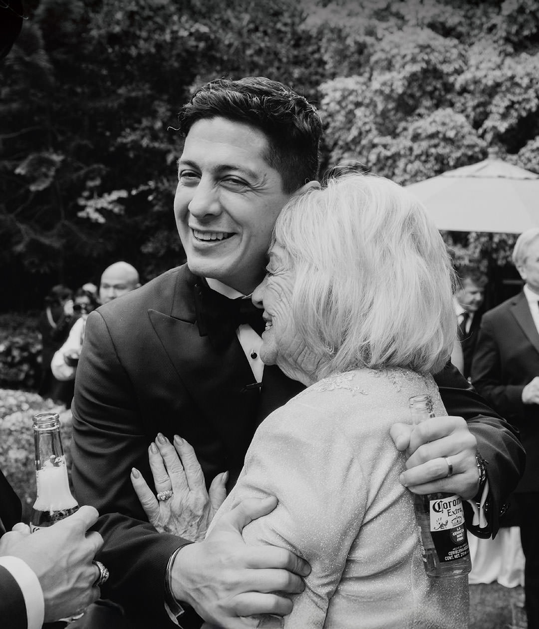 Groom hugging elderly woman at wedding. Documentary photography.