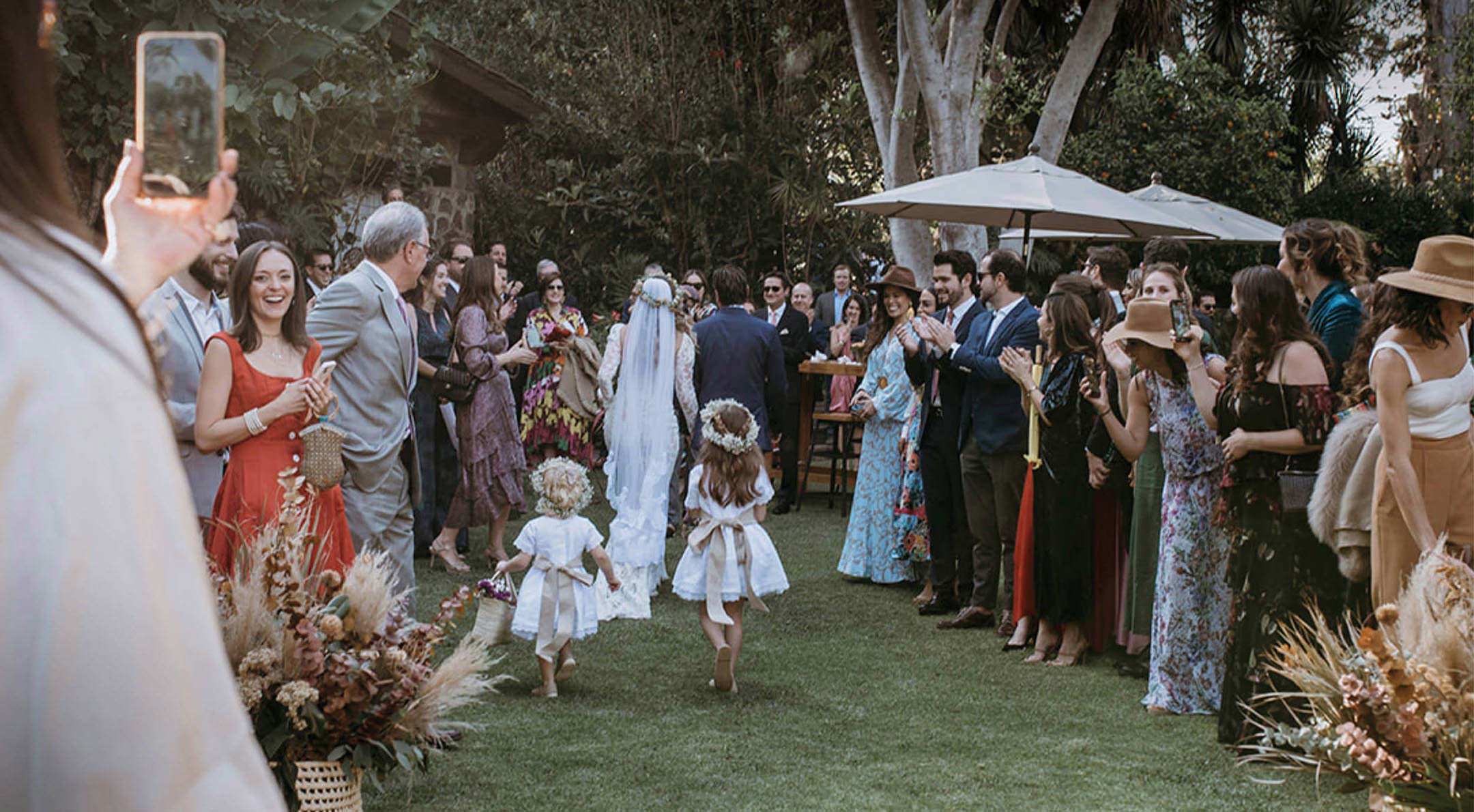 Breathless Weddings Two little flower girls walking ahead of the bride in a garden wedding.