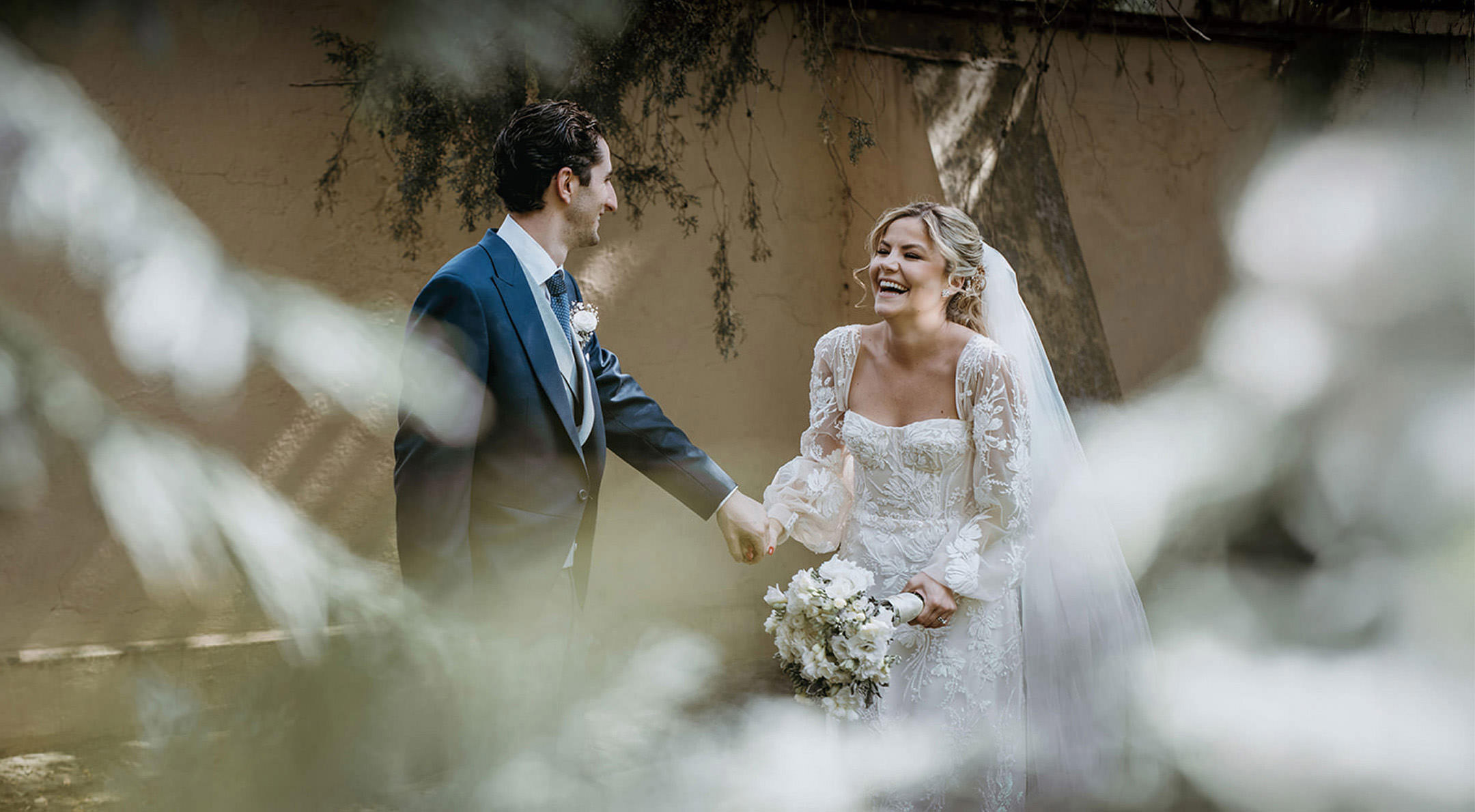 Breathless Weddings Bride laughing joyfully with the groom holding hands outdoors.
